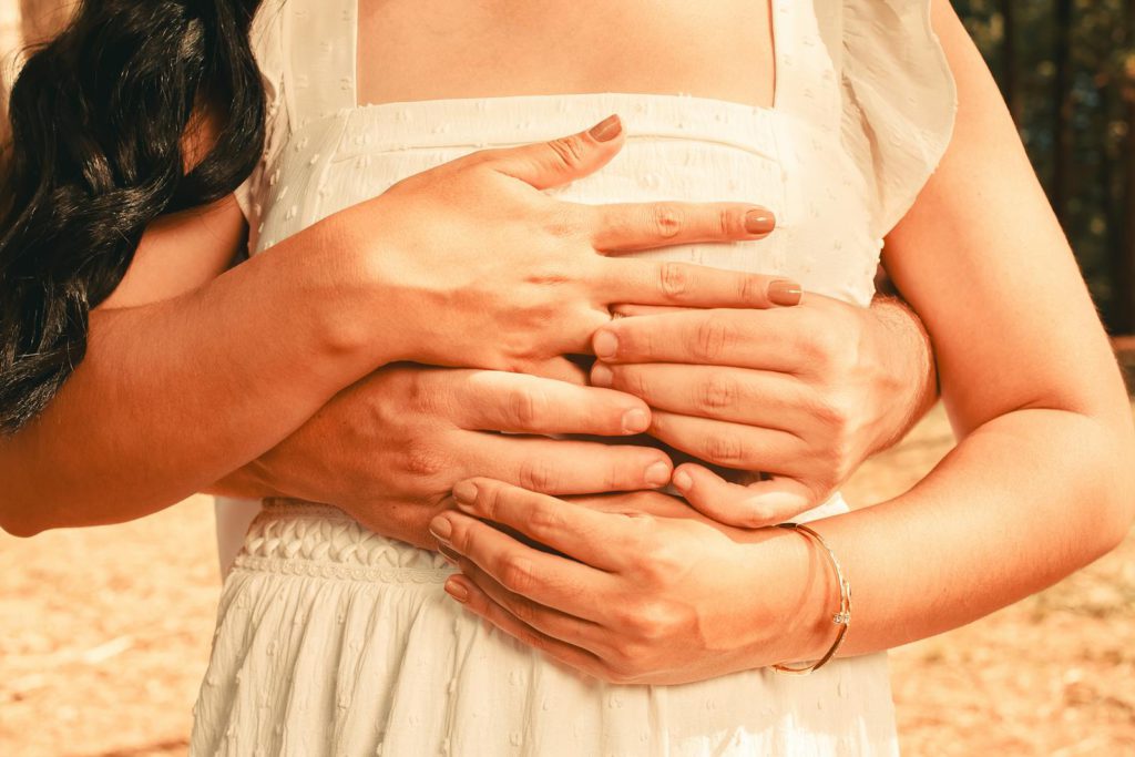 Close-up of a couple's embrace conveying love and warmth, captured in a sunlit setting.
