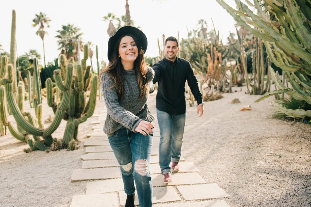 A joyful couple strolling on a sunny day among cacti, embracing leisure and love.